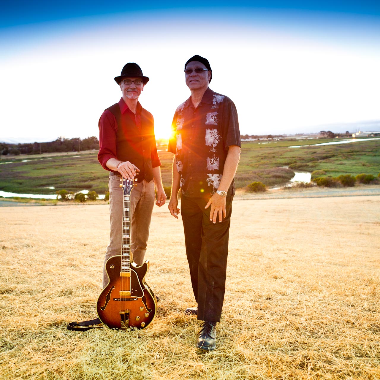 Nate Pruitt and Rick Vandivier with a guitar in a field.